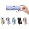 A hand holds a purple mini travel umbrella, showing various color options.