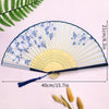A light blue and white lace fabric folding hand fan with a yellow edge displayed on a pink background.