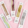 Ein Set Regenbogen-Spiral-Kerzen in verschiedenen Farben auf weißer Kartonverpackung.