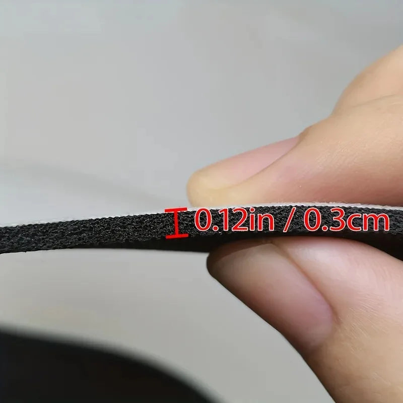 A hand measures a black bath mat, showing its thickness as 0.12 inches or 0.3 cm.