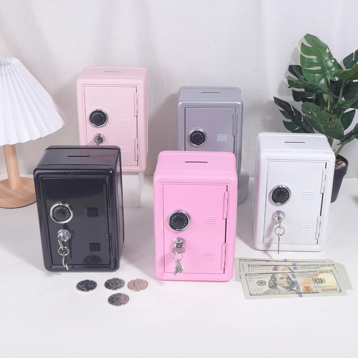 A collection of solid color metal piggy banks in pink, gray, and white, with coins and bills nearby.