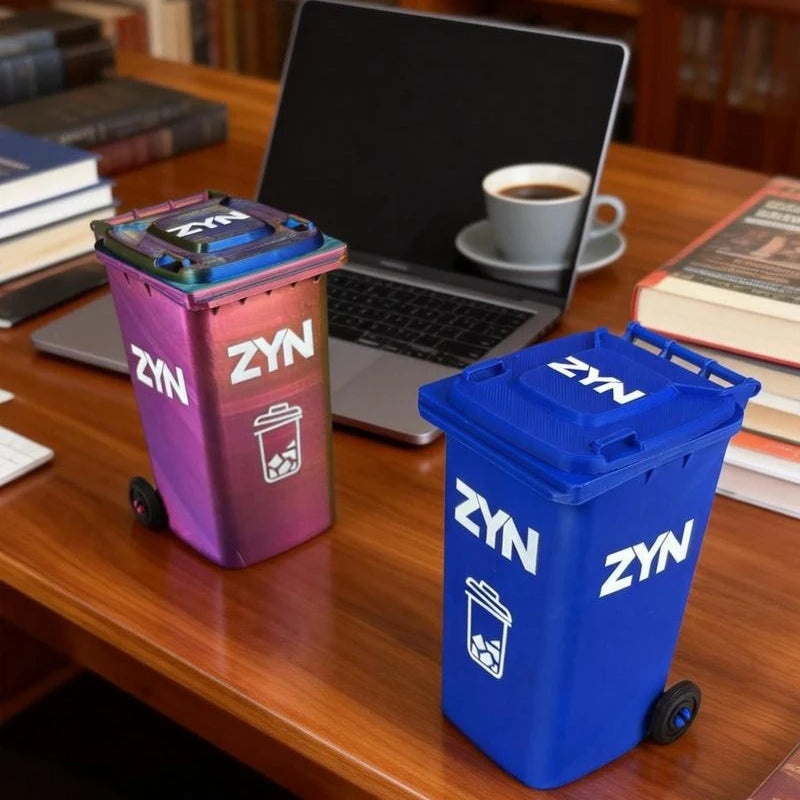 A blue mini desk organizer trash can with wheels sits on a wooden desk next to a laptop and coffee cup.