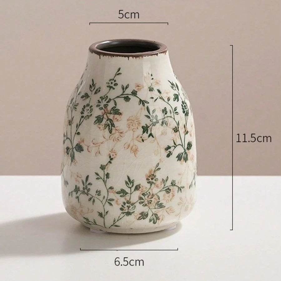 A ceramic bud vase with a speckled white glaze and green floral pattern, shown from the side.