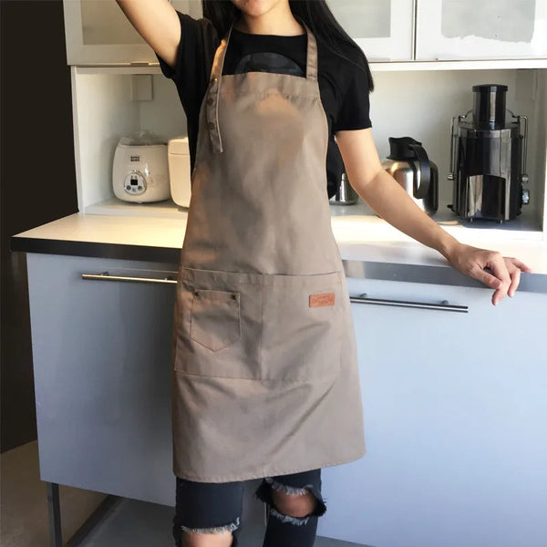 A person wearing a beige cotton kitchen apron stands in front of kitchen cabinets with appliances.