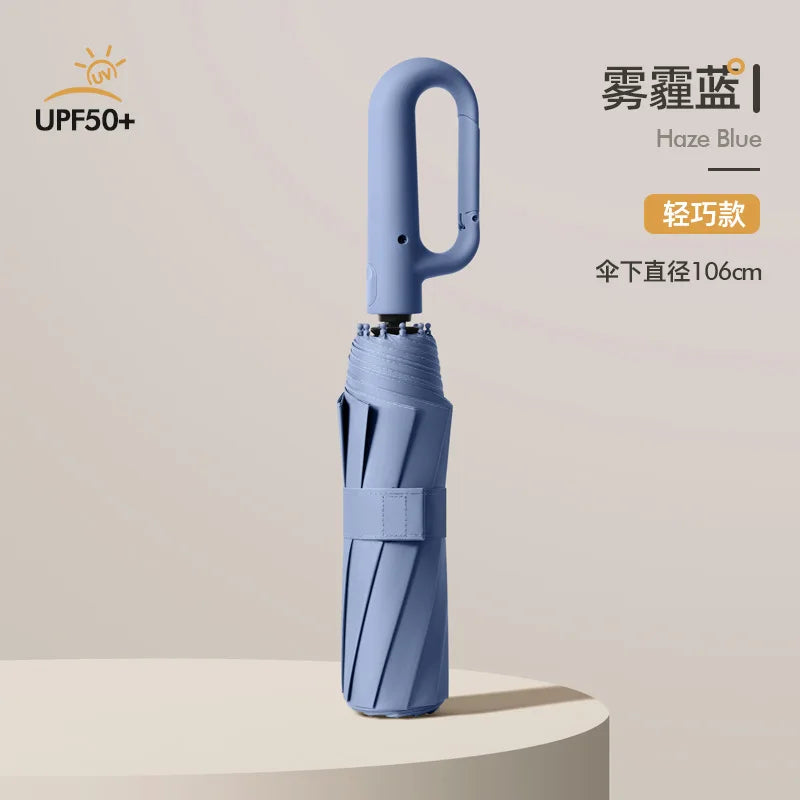 A light blue automatic folding umbrella with a reinforced shaft is shown standing on a surface.