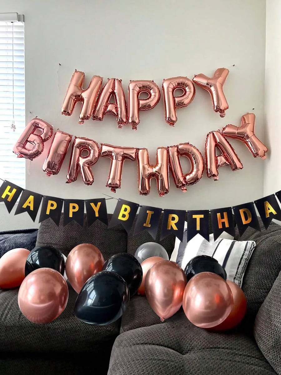 A decorative wall display of foil balloon letters spelling HAPPY BIRTHDAY in rose gold and pink tones.