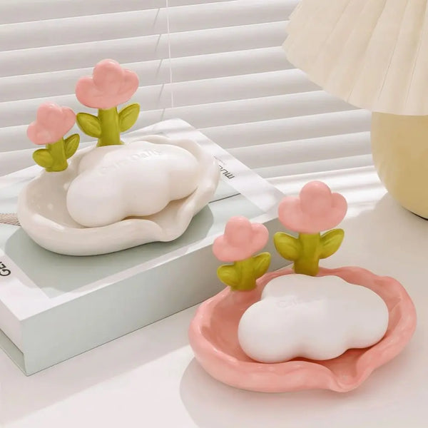 A pink decorative floral drain soap dish with a white cloud-shaped soap is shown on a light surface.