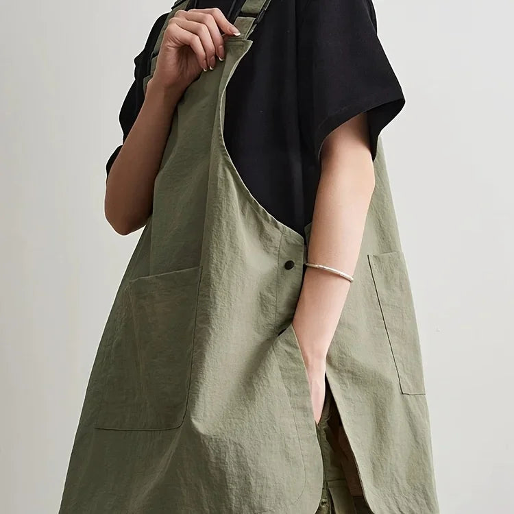 A person wearing a olive green waterproof outdoor work apron over a black shirt.