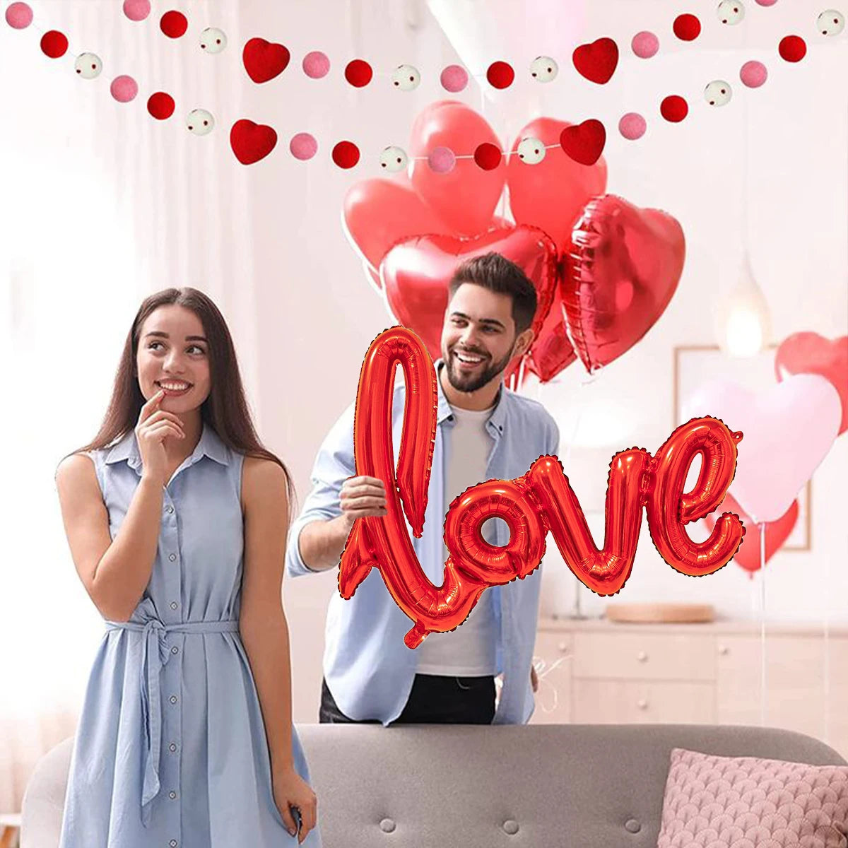 Junges Paar lächelt inmitten von roten und rosa herzförmigen Ballons für einen besonderen Anlass.