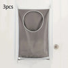 Three gray fabric laundry organizers with circular openings hanging on a white door.
