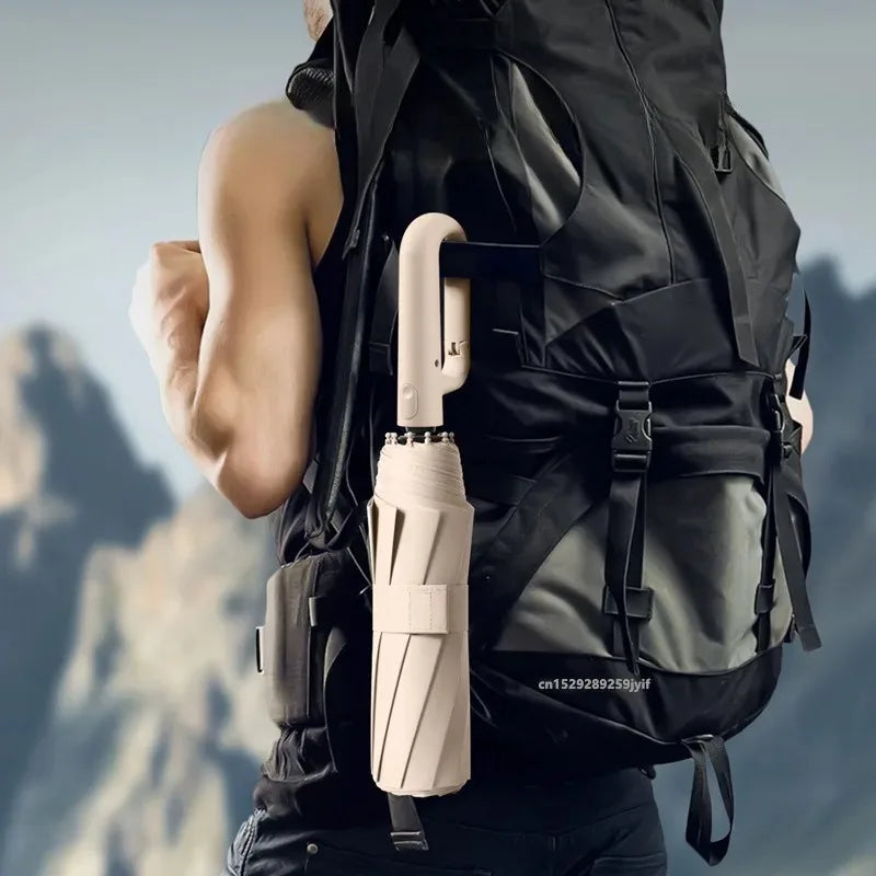 A close-up of a beige automatic folding umbrella attached to a black tactical vest.