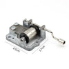 A silver hand crank mechanism for an antique wooden music box.