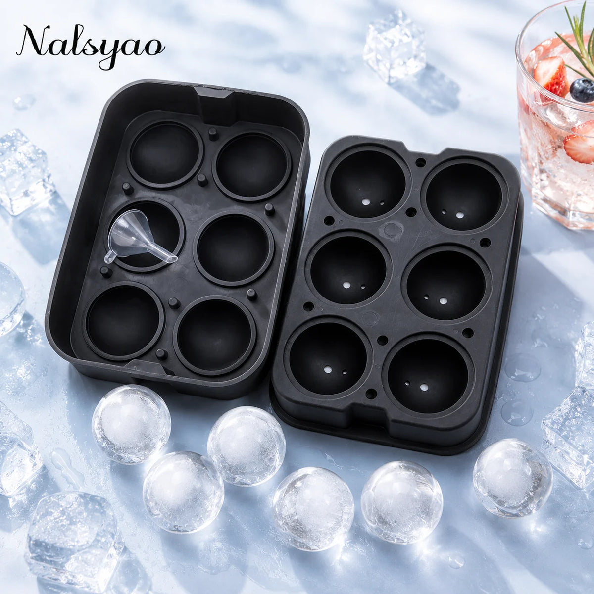 A black silicone ice mold tray with multiple spheres is shown next to a glass of iced drink on a frosty surface.