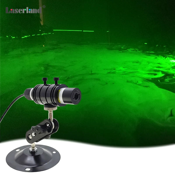 A black laser module mounted on a base, emitting a bright green beam in a dark environment.