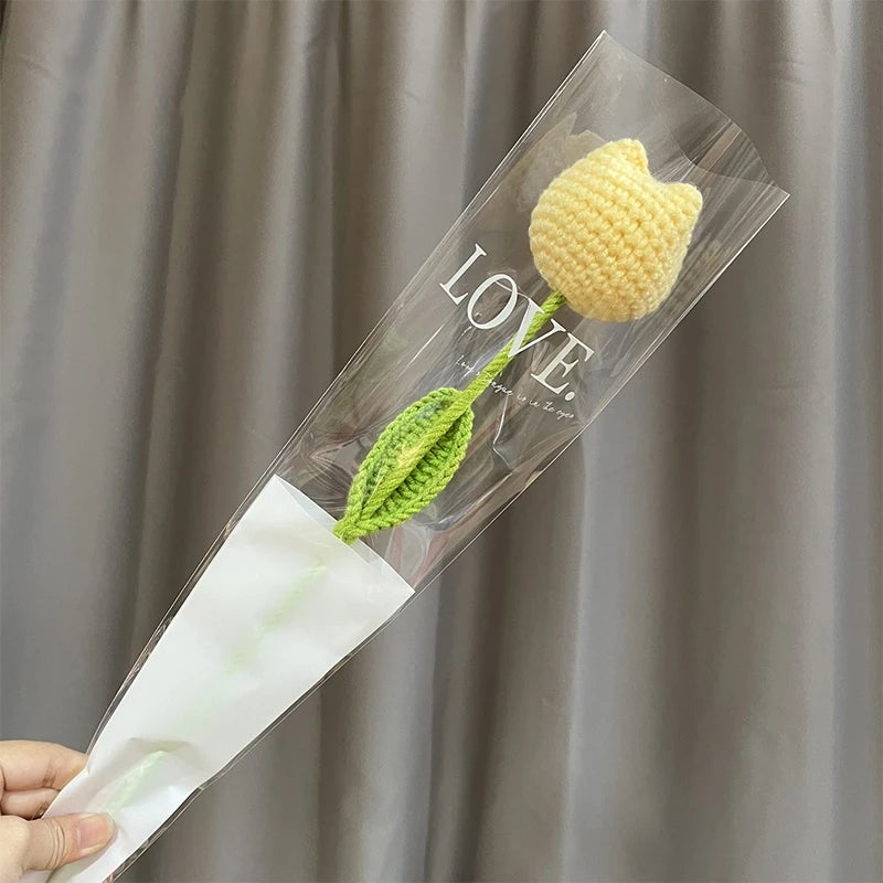 Bouquet de cœurs fait main en fleur de carnation, emballé dans du cellophane transparent avec une tige verte et le mot AMOUR 