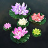 A collection of artificial lotus flowers in various shades of purple, pink, white, and green floating on dark water.