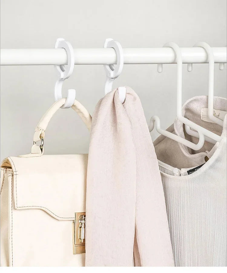 A light beige rotating closet organizer hook system mounted on a white bar, with a cream-colored bag and a pink garment hangi