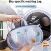A hand places a mesh bra-specific washing bag into the drum of a washing machine.