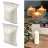 Dos bolsas blancas de material para hacer velas de cera de soja natural, junto a velas encendidas.