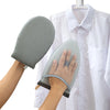 A hand holds a gray heat resistant ironing pad, which is attached to a white shirt hanging on a hanger.
