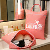 A pink laundry bag is displayed on a counter next to a mirror and other storage items.
