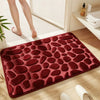 A deep red, pebble-textured bath mat is placed on a light wooden floor next to a white radiator.