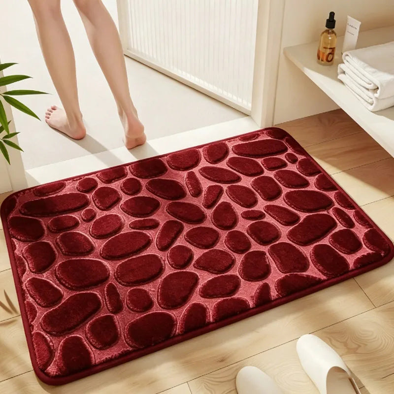 A deep red, pebble-textured bath mat is placed on a light wooden floor next to a white radiator.