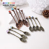A collection of natural crystal spoons with various colors and shapes displayed on a white background.
