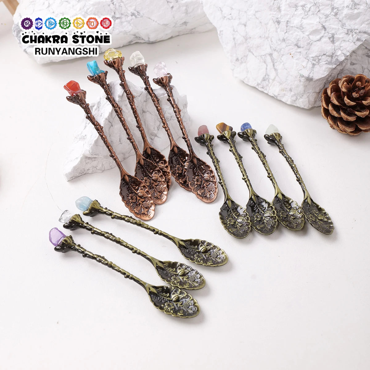 A collection of natural crystal spoons with various colors and shapes displayed on a white background.
