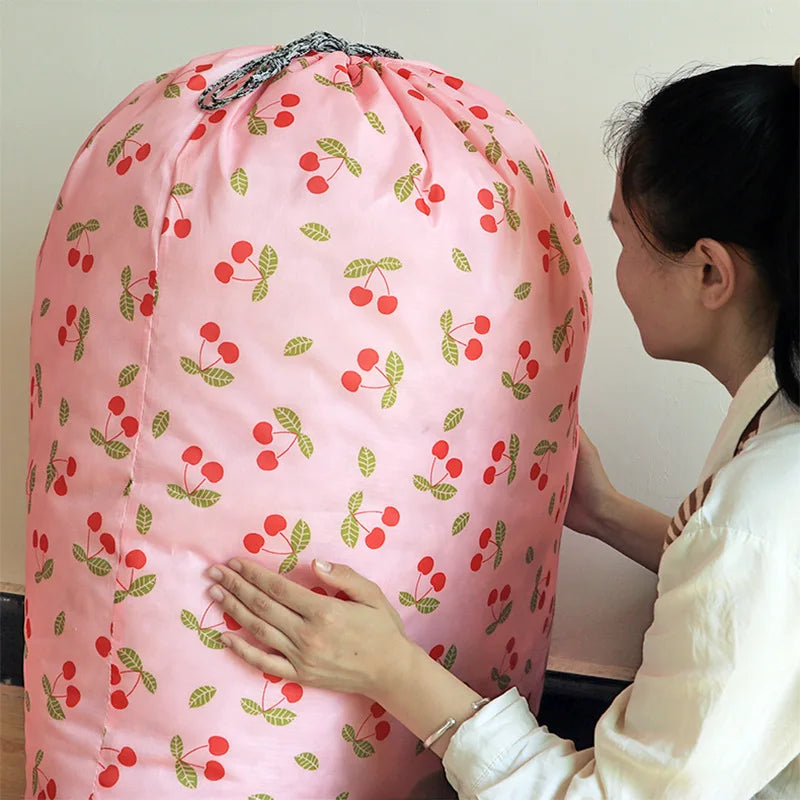 A pink drawstring storage bag filled with laundry or bedding, being held by a person.