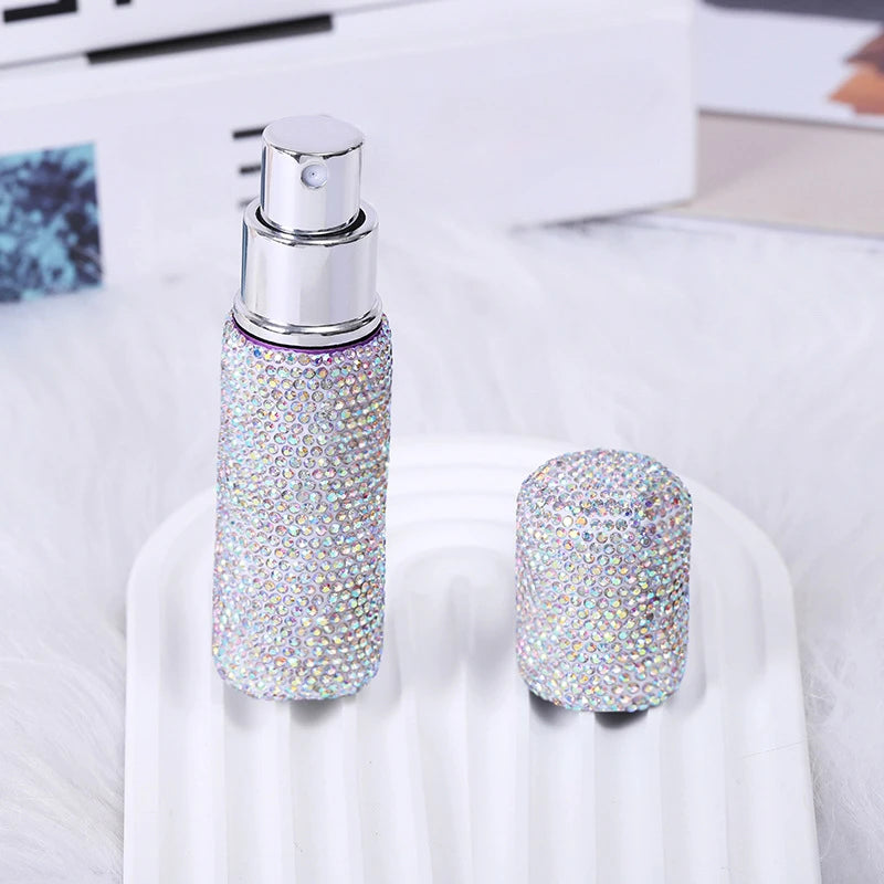 A silver glass perfume spray bottle with a purple glitter body is displayed on a white surface.