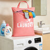 A pink laundry bag filled with colorful clothes rests on top of a white washing machine.