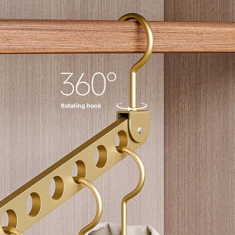 A gold-colored rotating hook hanger is shown hanging from a wooden rod, used for clothes storage.