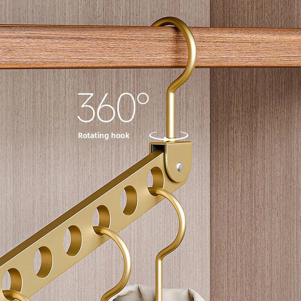 A gold-colored rotating hook hanger is shown hanging from a wooden rod, used for clothes storage.