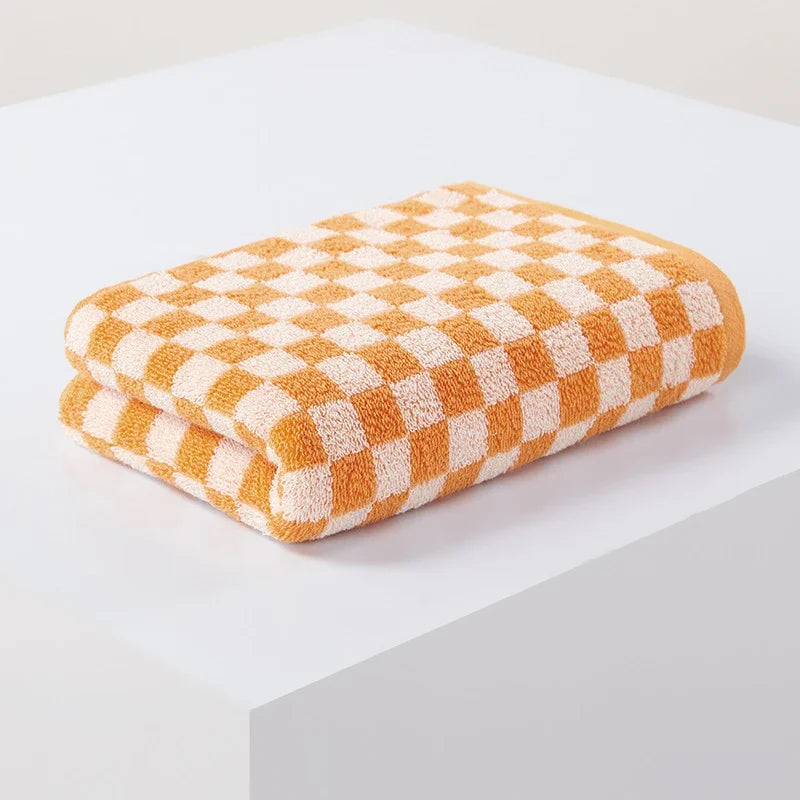 A stack of soft, orange and cream plaid cotton bath towels.