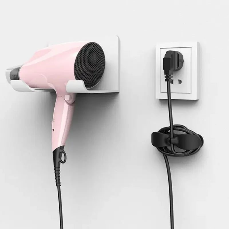 A pink reusable cable management organizer is mounted on a wall, showing its handheld unit and power cord.