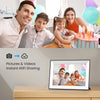 A family of three smiling while a digital photo frame displays a birthday cake.