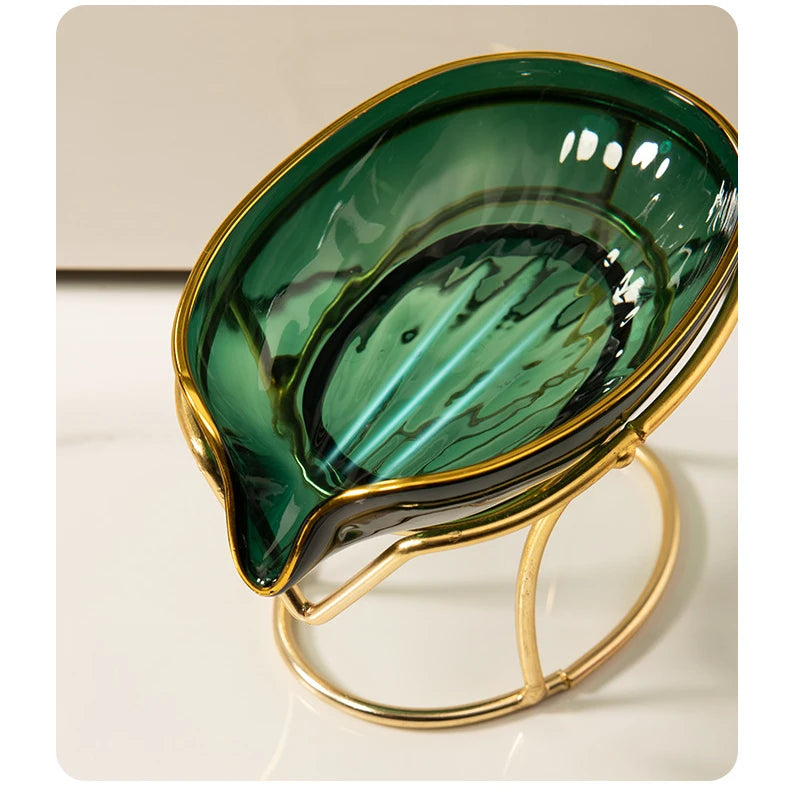 A glossy green leaf-shaped soap dish with a gold rim and stand.