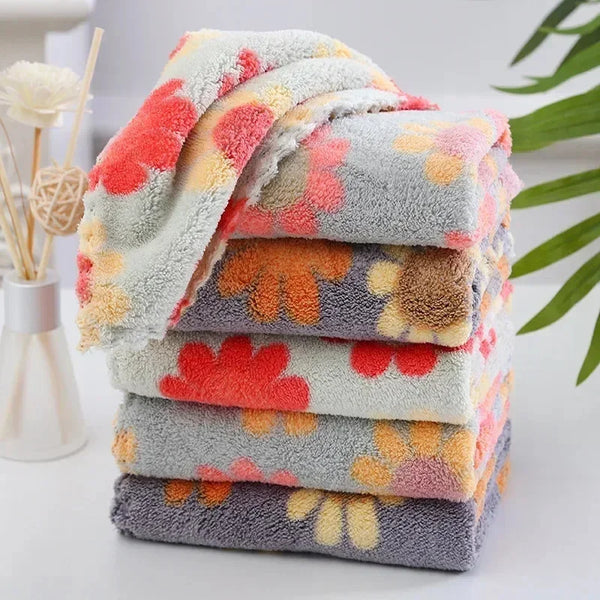 A stack of colorful, fluffy kitchen cleaning cloths in shades of pink, orange, and gray.