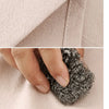 Close-up of a hand pulling a black, textured fabric from a light pink cotton kitchen apron.
