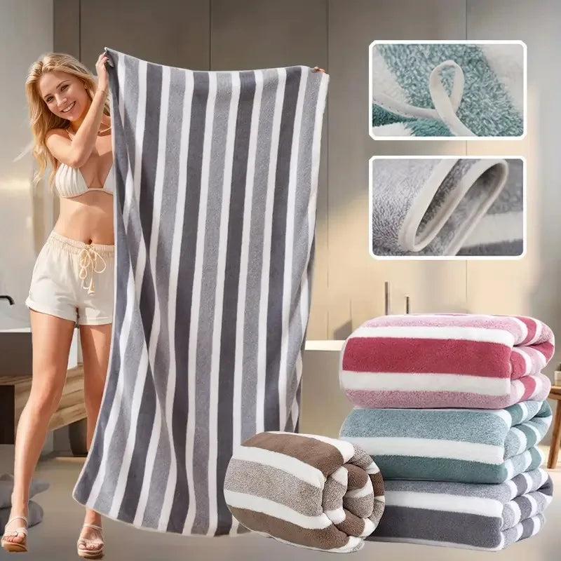 A woman models a gray and white striped microfiber bath towel set with stacked towels in various colors.