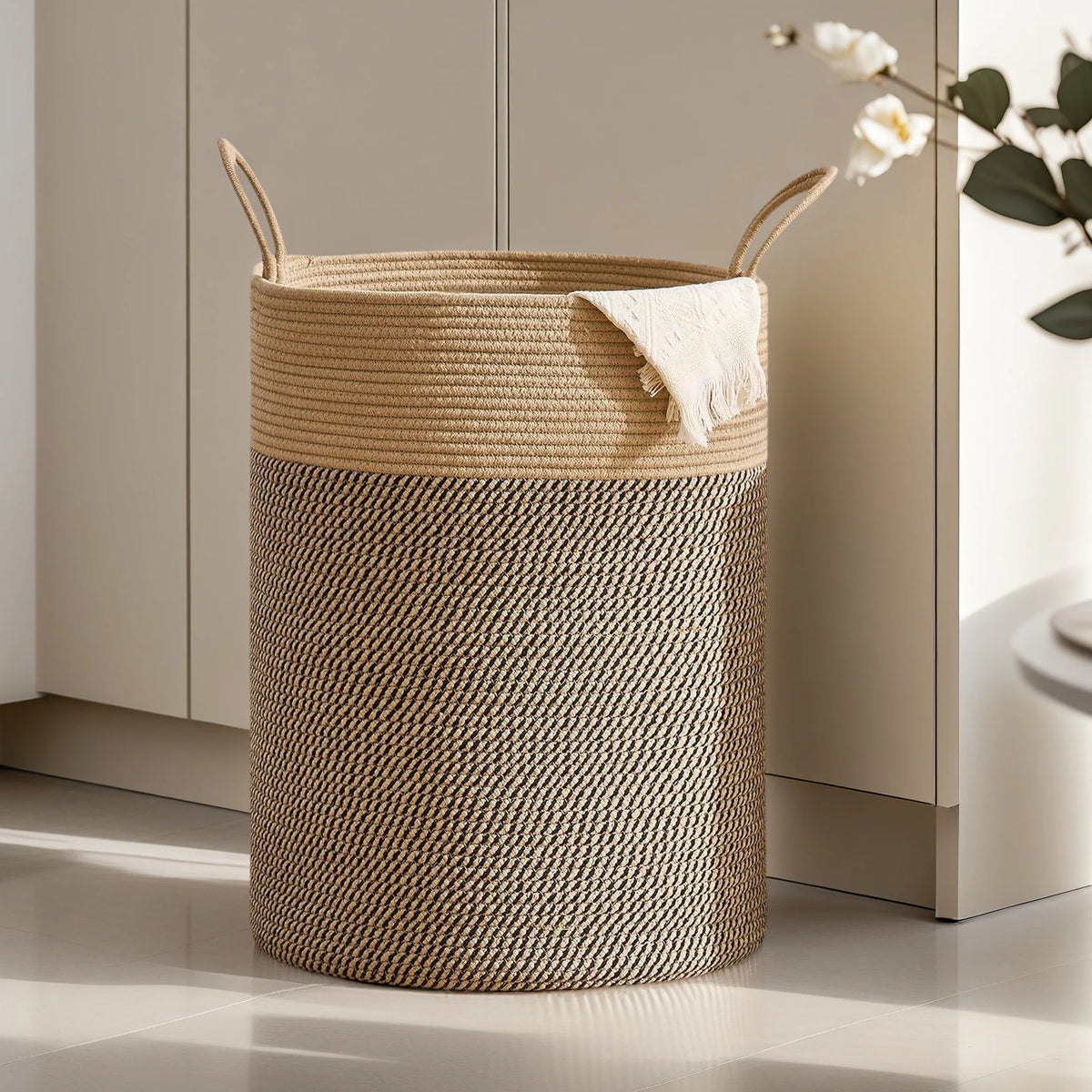 A large woven storage hamper with handles in natural beige and brown tones sits on a light floor.
