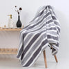 A gray and white striped bath towel draped over a wooden stand.