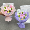 A bouquet of handmade crochet flowers in pink and yellow are presented in a paper wrapping.