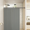 A black magnetic shower curtain with a waffle texture hanging in a modern bathroom.