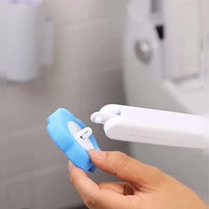 A hand is holding a white disposable toilet brush and holder set against a tiled wall.