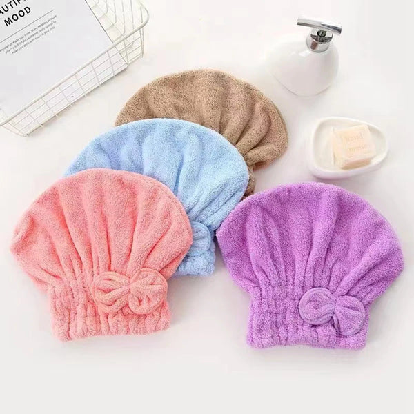 A collection of three fuzzy microfiber hair drying caps in shades of beige, light blue, and purple, with a small white soap d
