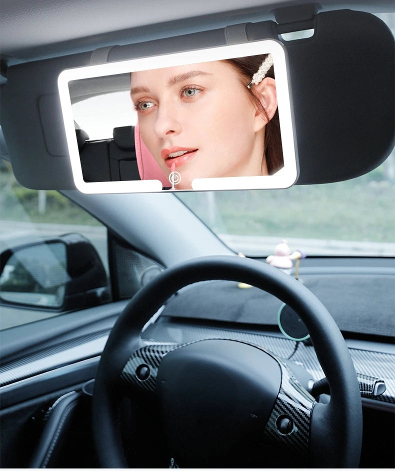 Espejo de maquillaje con luz LED montado en el interior de un coche, visible a través del parabrisas.