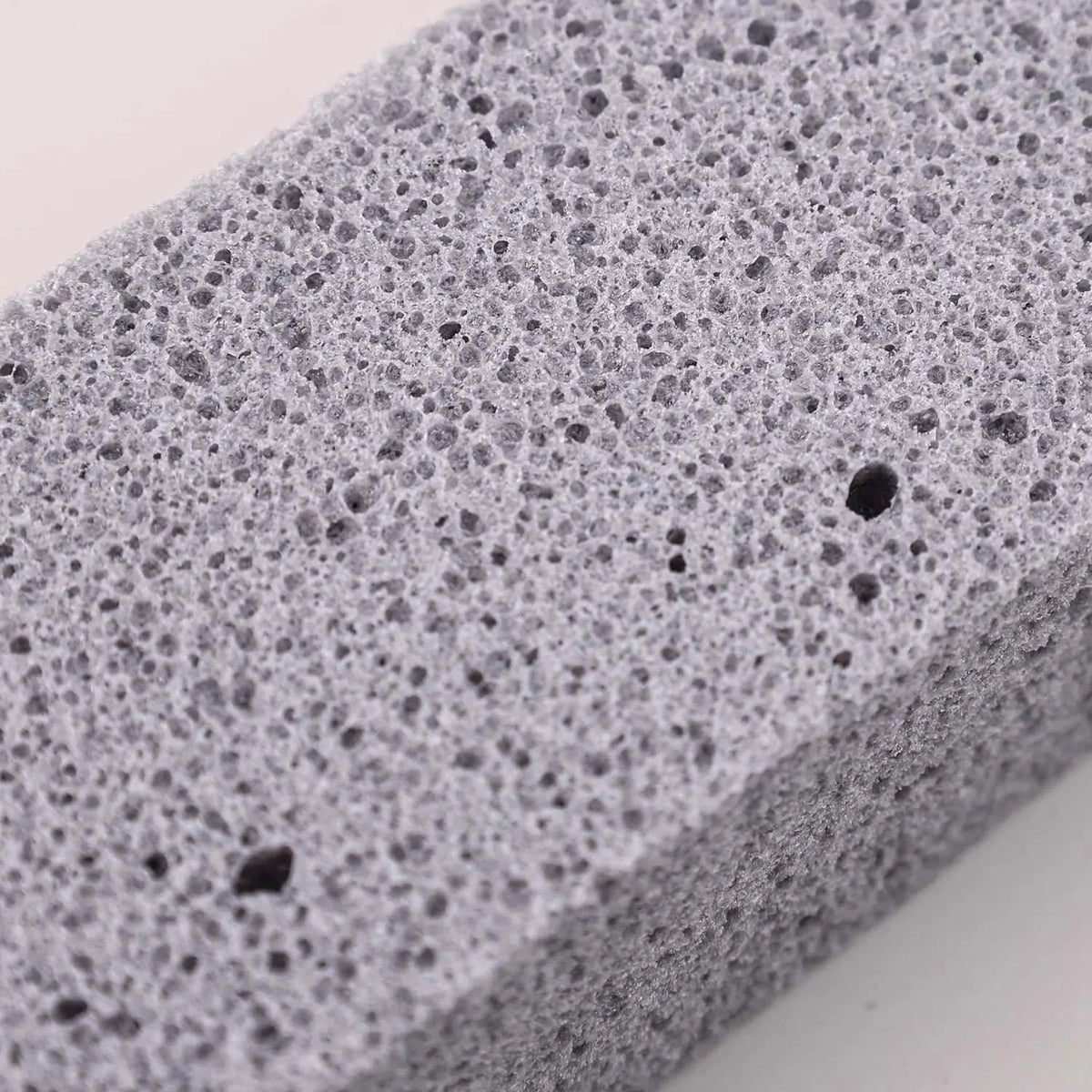 Close-up view of a gray reusable cleaning pumice stone stick with a porous texture.