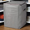 A checkered fabric foldable clothing storage bag sitting on a wooden shelf.